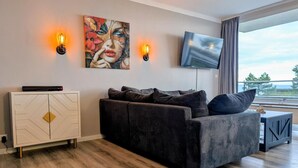 A modern living room with a sofa, a cabinet, a TV, and a painting on the wall.