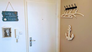 A hallway with a white door, a wall-mounted coat rack, a decorative anchor, and a small wall-mounted heater.