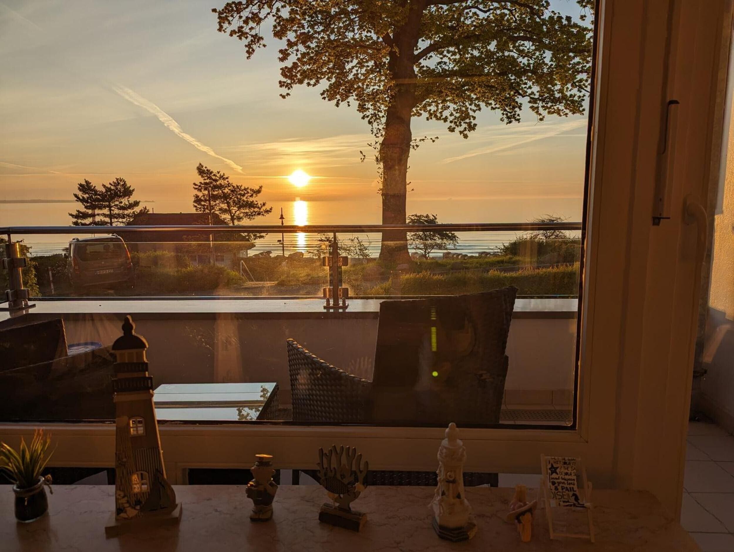 Una stanza con vista sul tramonto sull'acqua, un tavolo con oggetti decorativi e una finestra che si affaccia all'esterno.