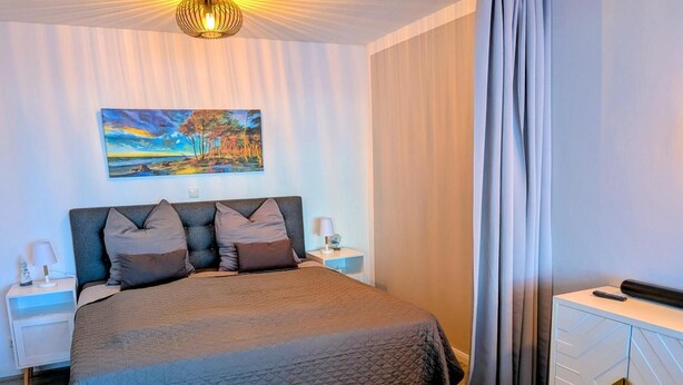 A bedroom with a bed, nightstands, a painting, and a dresser.