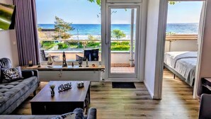 A modern room with a view of the sea, a sofa, a coffee table, and a bed.