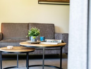 A modern living room with a grey sofa, two round tables, and a small potted plant. - 6-person Bungalow With Field Views (Oostkapelle)