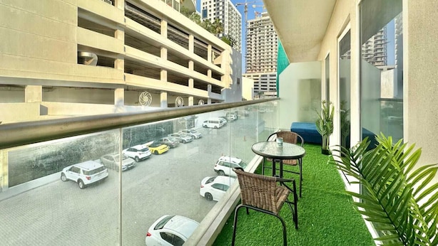 A balcony with a view of a multi-level parking garage and a busy road.