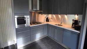 Uma cozinha moderna com armários cinza, eletrodomésticos de aço inoxidável e iluminação sob os armários.