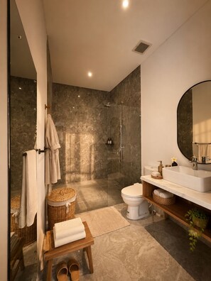 A modern bathroom with a glass-enclosed shower, a white toilet, a vanity with a large mirror, and a wooden bench with towels. - Private Pool & Paddy Sunsets - Canggu (Canggu)