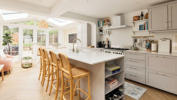 A modern kitchen with a large island, white cabinetry, and a dining area with wicker chairs. - New! Elegant 3BR w/Garden near Crystal Palace Park (Greater London)