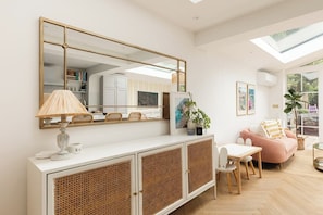 A modern living room with a large mirror, a white console table, a pink sofa, and a dining area. - New! Elegant 3BR w/Garden near Crystal Palace Park (Greater London)