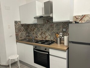 A compact kitchen with a gas stove, oven, and a refrigerator. - MammanaSuite, 3 minutes from Uditore Park (Palermo)