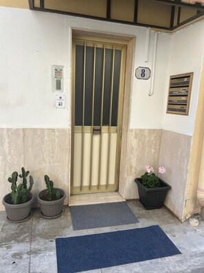 A building entrance with a metal gate, a mailbox, and potted plants. - MammanaSuite, 3 minutes from Uditore Park (Palermo)