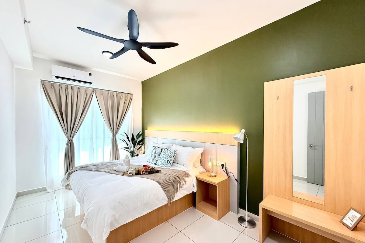 A modern hotel bedroom with a bed, bedside table, nightstand, ceiling fan, and a large mirror.