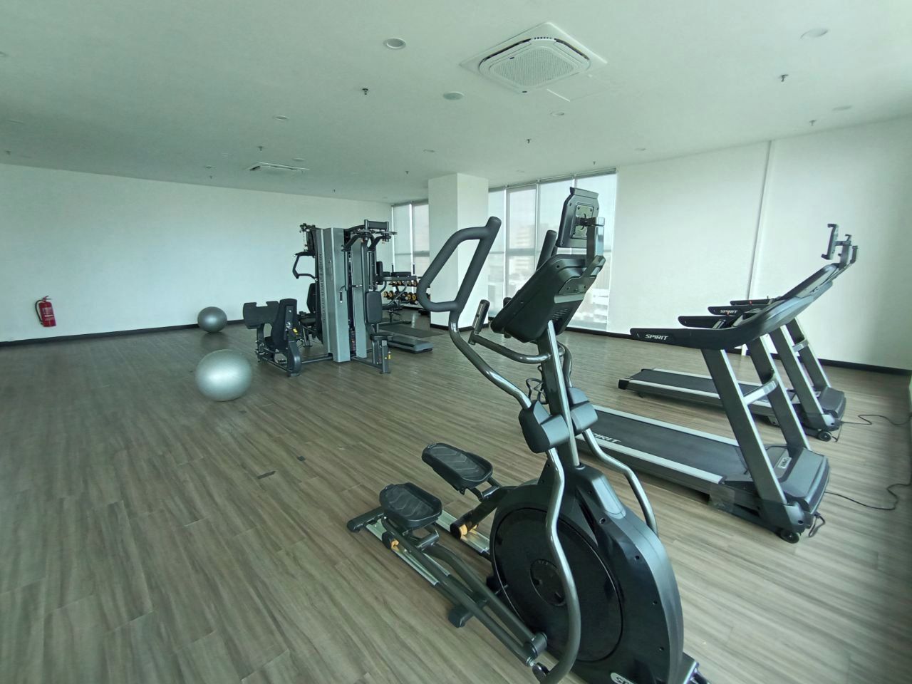 Un gimnasio con cintas de correr, elípticas y pesas libres.