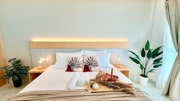 A hotel room with a bed, nightstands, a bedside lamp, a potted plant, and a window with curtains.