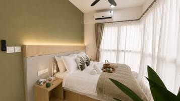 A bedroom with a bed, bedside table, nightstand, ceiling fan, air conditioning unit, and a window with curtains.