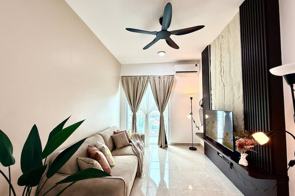 A modern living room with a sofa, TV, ceiling fan, and large windows with curtains.