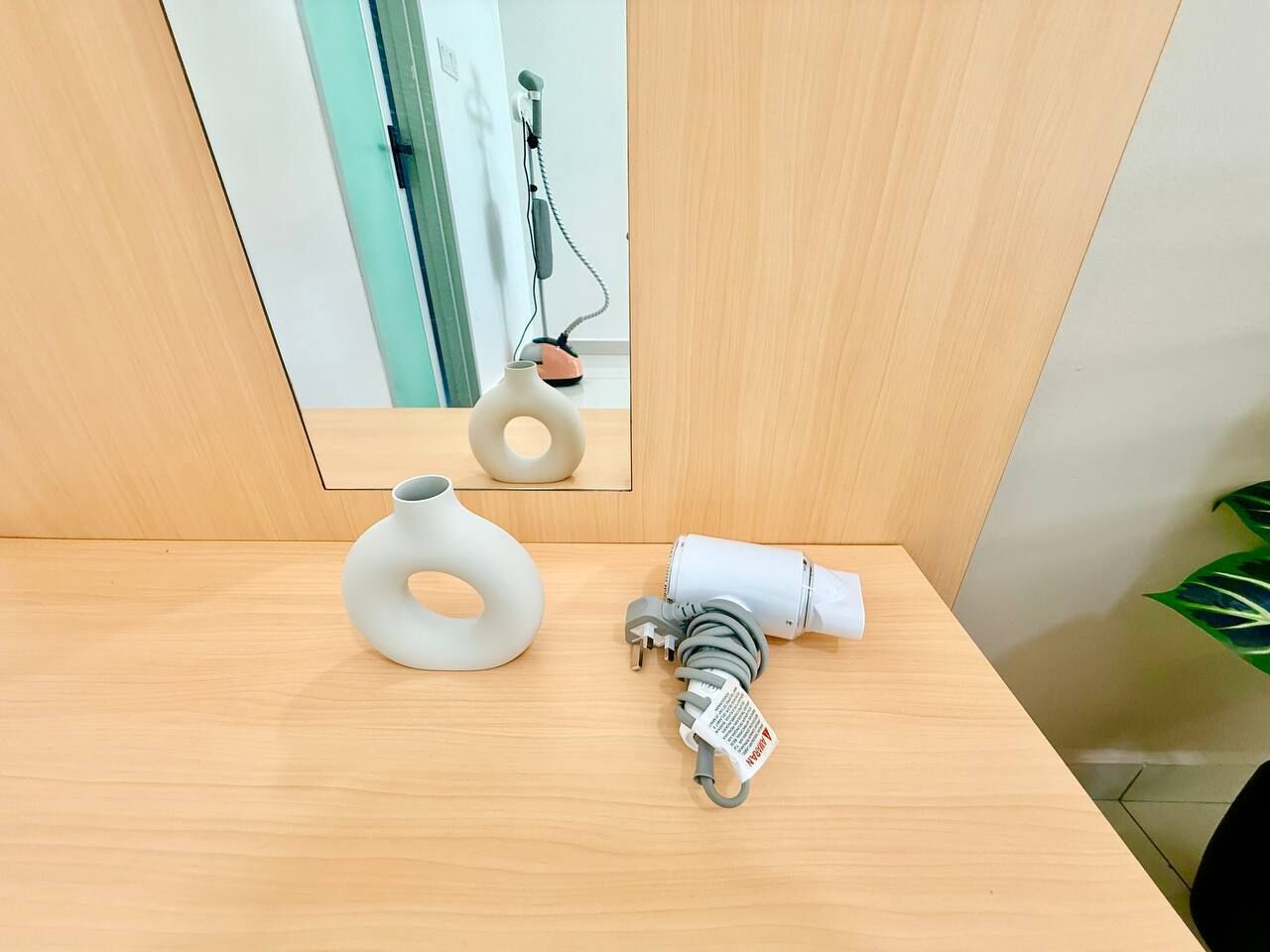 A wooden table with a white vase and a power strip with a cable.