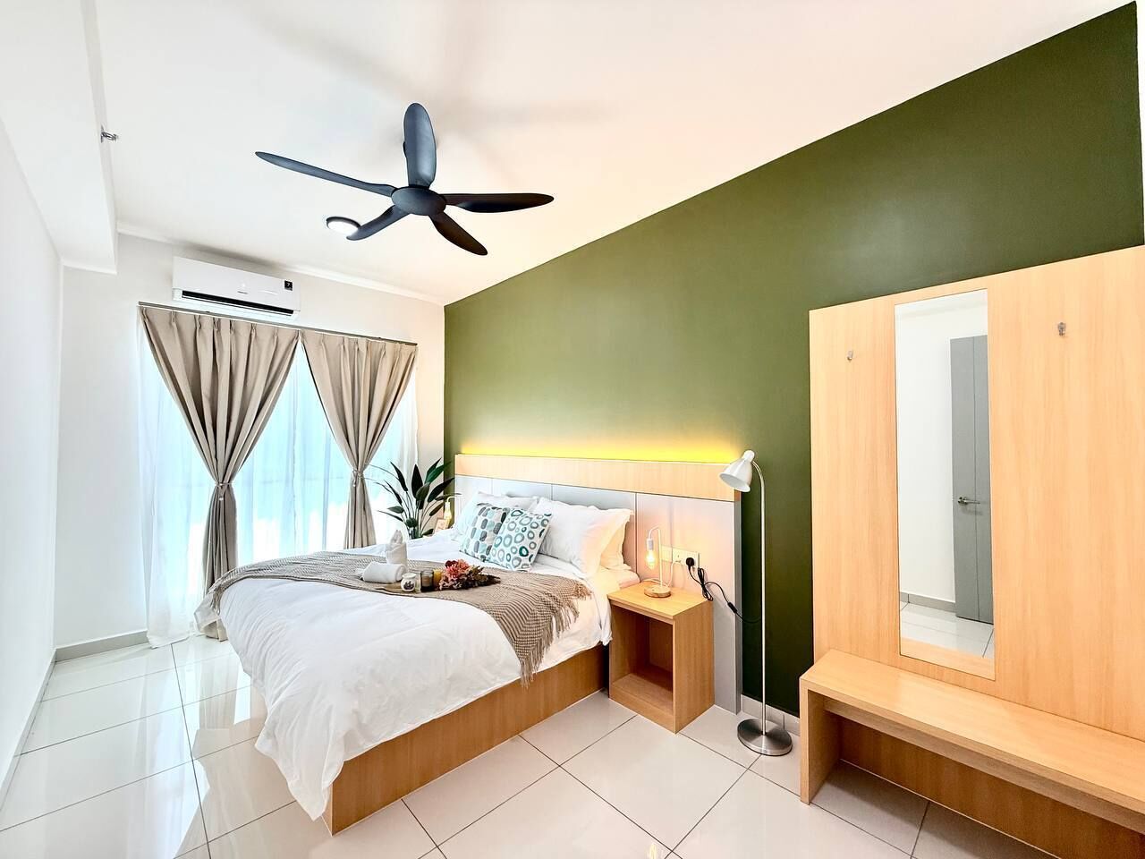 Une chambre moderne comprenant un lit, une table de chevet, une commode, un ventilateur de plafond et un grand miroir.