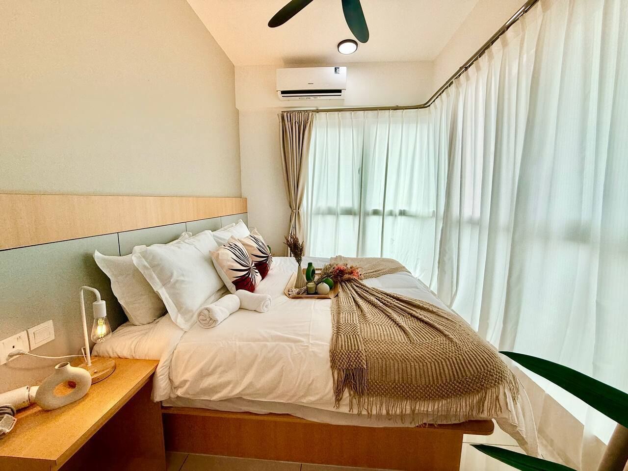 Et moderne hotelværelse med seng, natbord og ventilator i loftet.