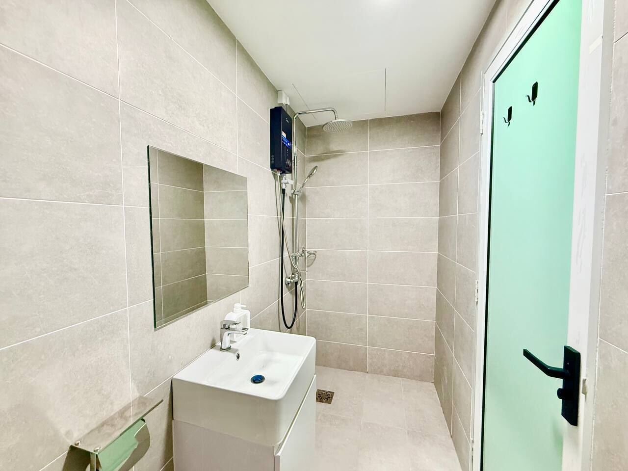 A bathroom with a sink, mirror, shower, and a green door.