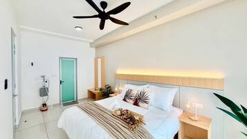 A modern bedroom with a bed, bedside tables, a ceiling fan, and a green door.