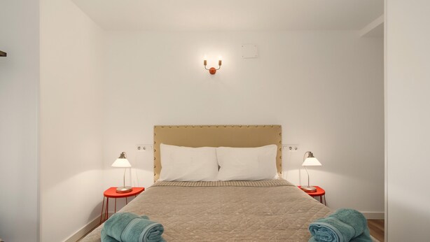 A hotel room with a bed, two bedside tables with lamps, and a wall-mounted light fixture. - Apartment with Mountain Views, Balcony, and Wi-Fi (Ampuero)