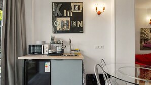 A compact kitchen with a refrigerator, microwave, and a sink. There is a wall-mounted light fixture and a framed artwork above the counter. - Apartment with Mountain Views, Balcony, and Wi-Fi (Ampuero)