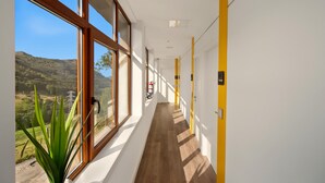 A corridor with large windows, a plant, and doors numbered 112 and 109. - Apartment with Mountain Views, Balcony, and Wi-Fi (Ampuero)