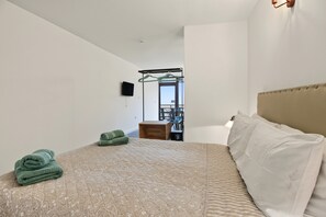 Un dormitorio con una cama, un perchero, un escritorio y una silla.