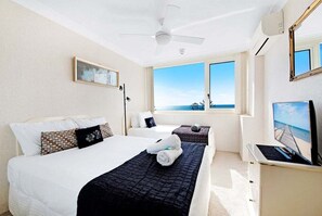 A hotel room with two beds, a ceiling fan, an air conditioning unit, a TV, and a window with a view of the ocean. - Beachside Getaway, Southern Cross Seventh Floor (Gold Coast)