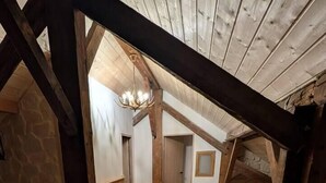 Um quarto com teto inclinado, vigas de madeira e um painel de chão de vidro.