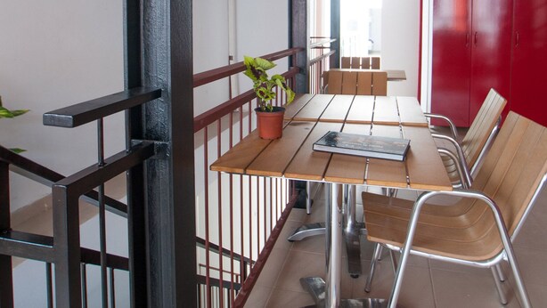 A room with a wooden table, chairs, a potted plant, a red cabinet, and a ceiling with exposed beams. - Pura Vida by Nest Hostel (Las Palmas de Gran Canaria)