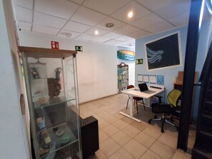 A room with a glass display case, a desk with a laptop, and a chair. - Pura Vida by Nest Hostel (Las Palmas de Gran Canaria)