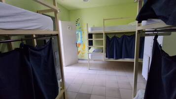 Habitación tipo dormitorio con literas, taquillas y una puerta que da a un baño.