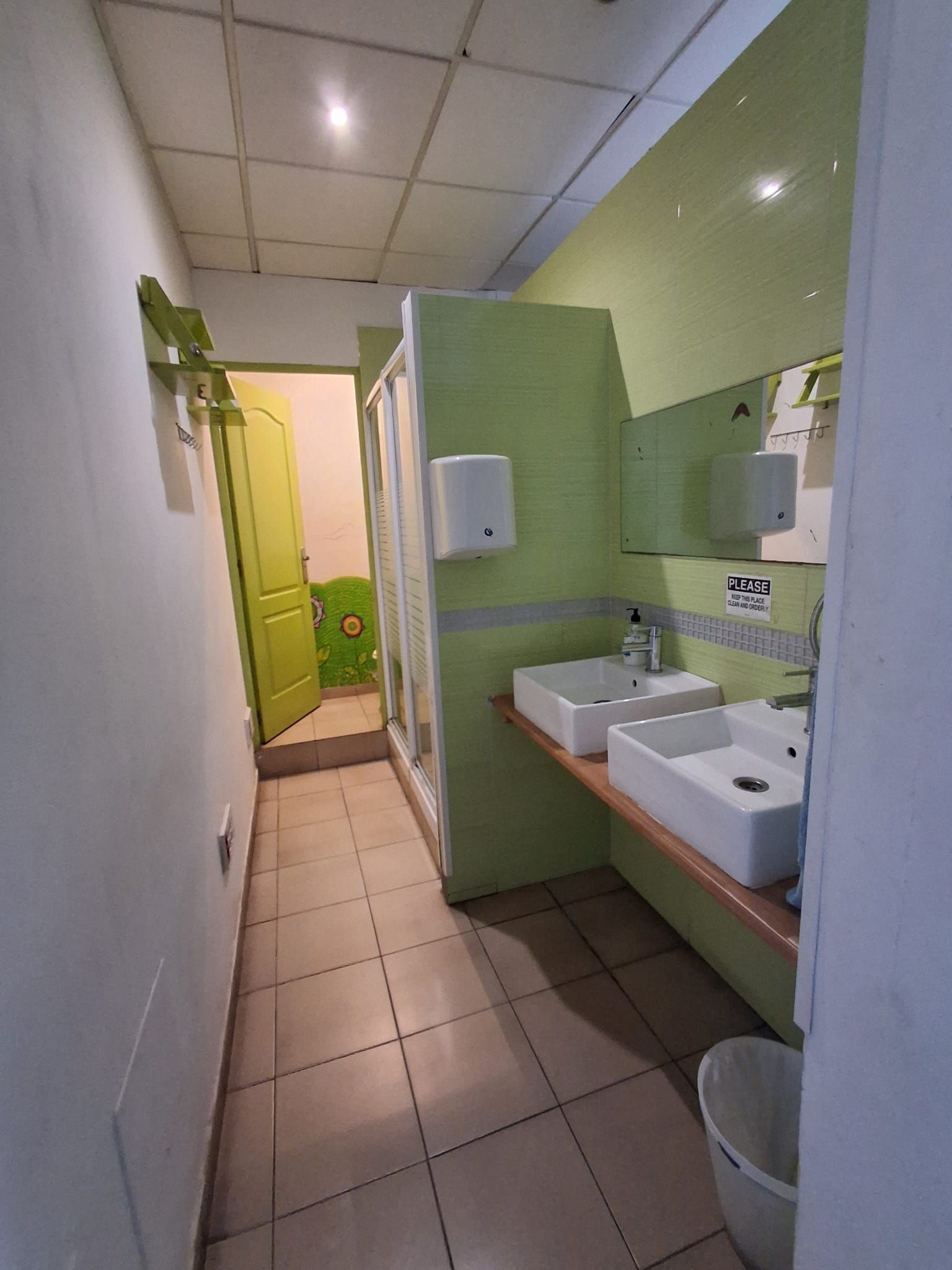 A bathroom with two sinks, a toilet, and a trash bin.