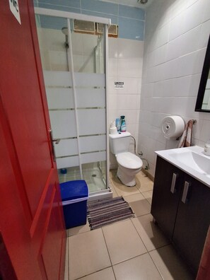 A bathroom with a toilet, sink, and shower area. - Pura Vida by Nest Hostel (Las Palmas de Gran Canaria)