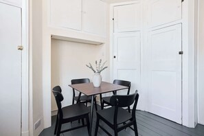 Ein Zimmer mit einem Esstisch, vier Stühlen, einer Pflanze in einer Vase und weißen Türen.
