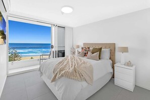 Ein Schlafzimmer mit einem großen Bett, einem Nachttisch und Blick aufs Meer.