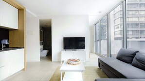 Een moderne woonkamer met een flatscreen televisie, een grijze bank en een kleine witte tafel met een taart.