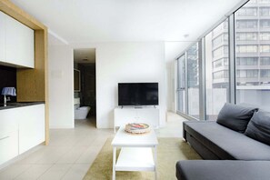 Ein modernes Wohnzimmer mit einem Flachbildfernseher, einem grauen Sofa und einem kleinen weißen Tisch mit einer Torte.