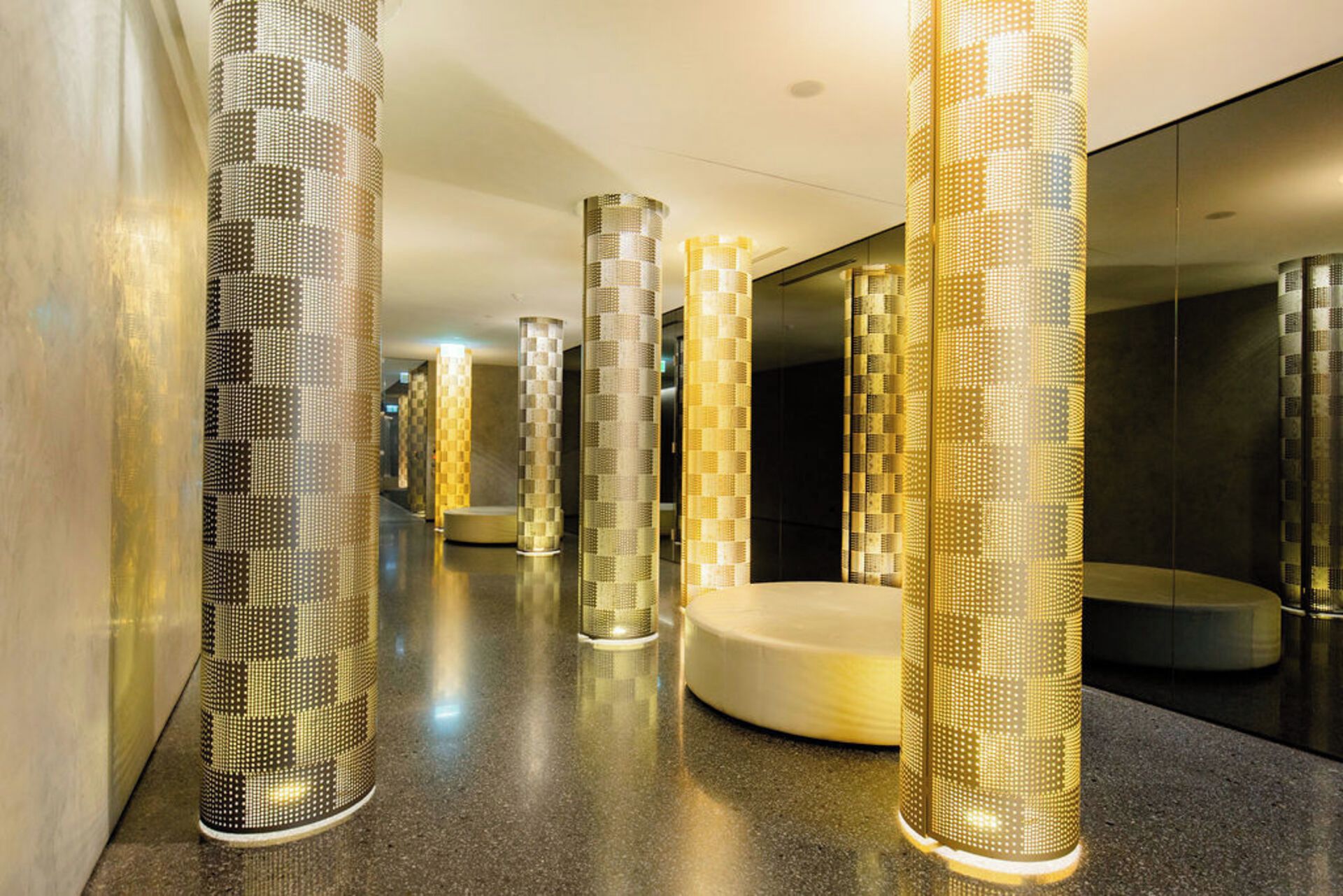 A corridor with tall, cylindrical columns and a round seating area.