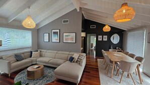 Een moderne woonkamer met een hoekbank, een eettafel met stoelen, en een keuken in de achtergrond.