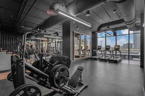 A gym with weightlifting equipment, treadmills, and large windows offering a city view. - Skyline Miami & Resort Amenities (Miami)