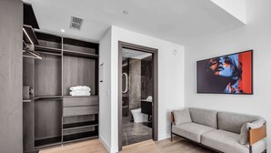 A modern interior with a walk-in closet, a gray sofa, and a large abstract painting. - Skyline Miami & Resort Amenities (Miami)