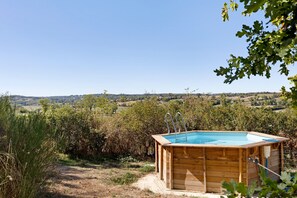 A wooden hot tub with a clear view of a rural landscape in the background.