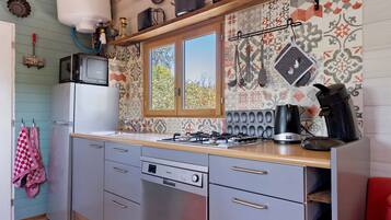 A kitchen with a gas stove, a microwave, and a refrigerator.