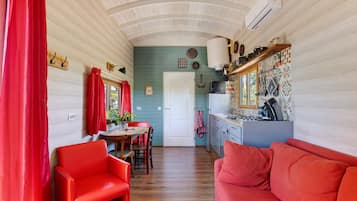 Een compacte keuken met een eethoek, met een houten plafond, een witte deur en een rode bank.