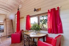 A cozy room with a wooden table, red chairs, a window with curtains, and a plant on the windowsill.