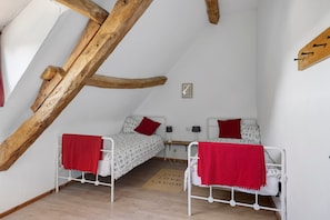 Ein kleiner, gemütlicher Raum mit zwei Einzelbetten, einem Holzbalken an der Decke und einem kleinen Bild an der Wand.