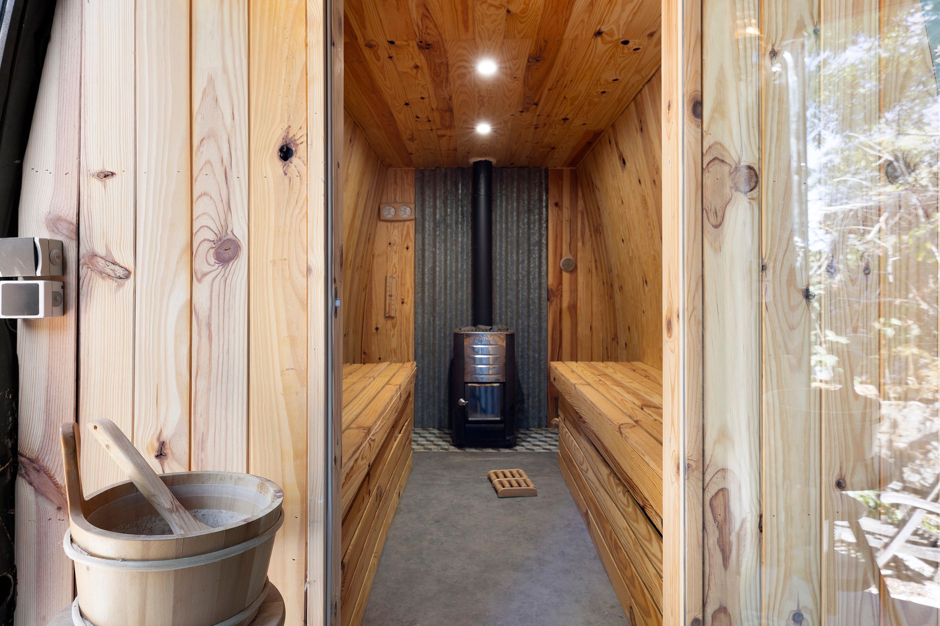 A sauna room with wooden walls and a central heating unit.