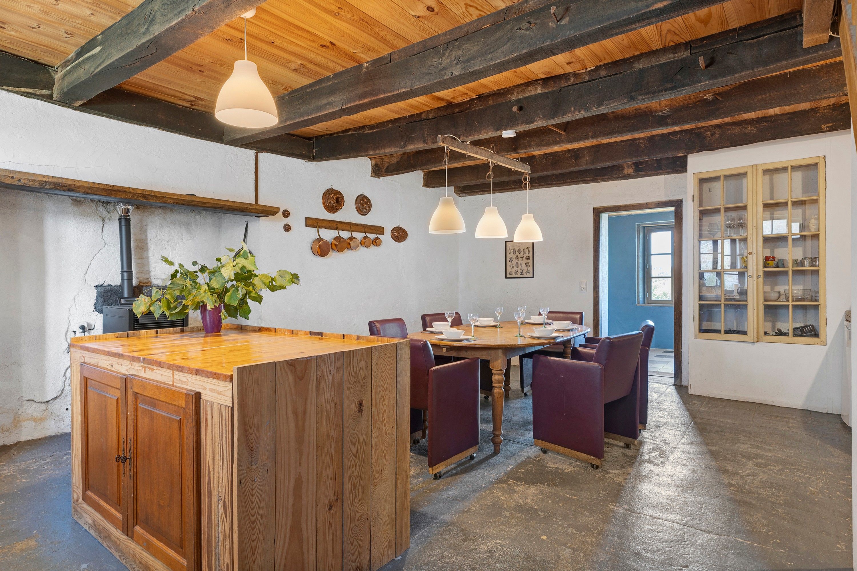 A rustic kitchen with wooden beams, a central island, and pendant lighting.
