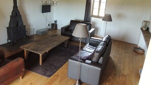 Ein gemütliches Wohnzimmer mit Kamin, Sofa, Tisch und Lampe.